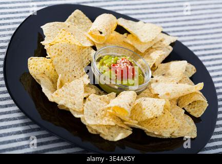 Nachos chips with sauces on black plate Stock Photo