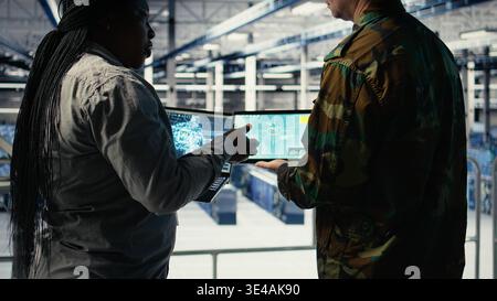 Close up of military data center colleagues looking at radar software to watch for enemy threats. Teamworking army staff members in data center scan suspicious activity to detect dangers, camera A Stock Photo