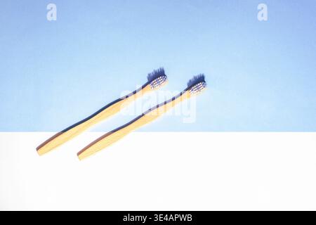 Two wooden toothbrushes on blue and white background with light and shadows. Eco friendly oral hygiene concept. Top view, flat lay, copy space. Stock Photo