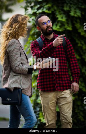 Casual outdoor conversation between two stylish professionals engaging with technology Stock Photo