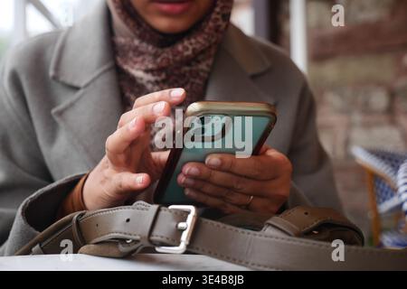 Woman using smartphone at a cafe in a city Stock Photo