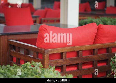 Outdoor seating area with red cushions near plants Stock Photo