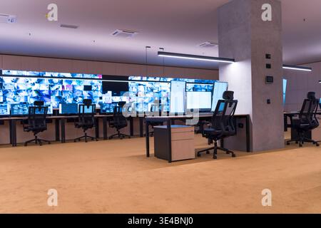 Modern security operations center with multiple workstations and large video wall displaying surveillance camera feeds. Concept of monitoring, safety, Stock Photo