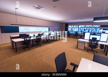 Modern security operations center with multiple workstations and large video wall displaying surveillance camera feeds. Concept of monitoring, safety, Stock Photo