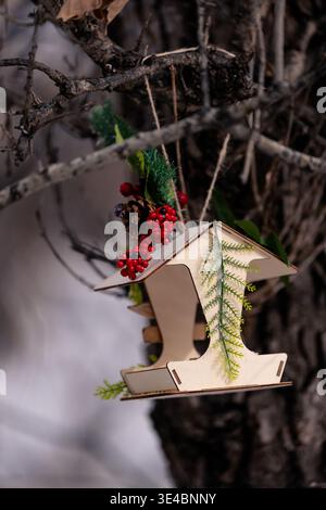 A small wooden birdhouse hangs from a tree branch in a quiet winter forest Stock Photo