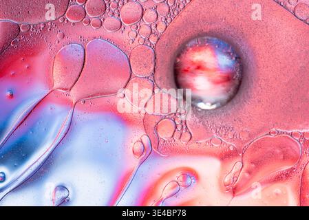 High detail macro shot of oil droplets on water with blue and pink light reflecting in the spheres. Stock Photo