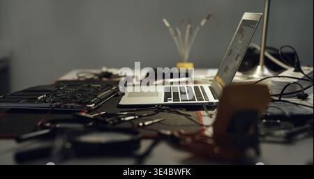 Laptop, repair and work desk with components for electronic maintenance or fix in workshop. Empty, computer or IT engineering with equipment for Stock Photo