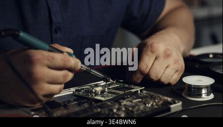 Soldering, repair or hands in workshop with circuit board, inspection or wiring assemble in hardware check. Electronics, man or engineer with tech Stock Photo