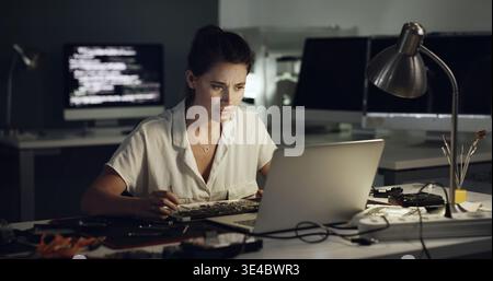 Tool, motherboard and woman with laptop repair in office for diagnostic solution, hardware test and IT. Tech, technician and install CPU at night for Stock Photo