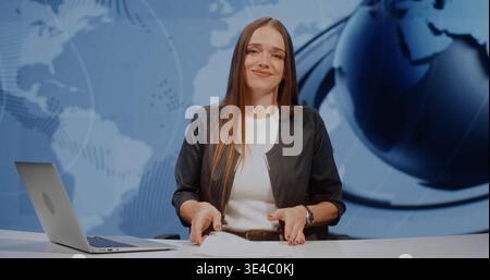 Professional Woman Anchor in Grey Jacket Looks at Camera With Smile, Finishing Report and Straightening Stack of Papers. Media Journalism Concept in Modern High Tech Studio With Large LED Screen. Stock Photo