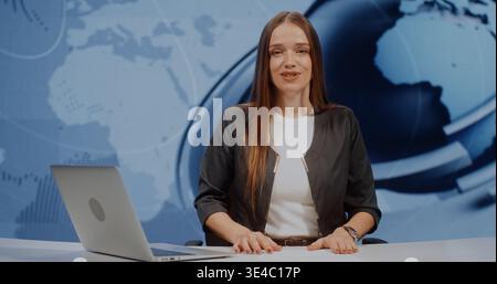 Professional Woman Anchor in Grey Jacket Looks at Camera With Smile, Finishing Report and Straightening Stack of Papers. Media Journalism Concept in Modern High Tech Studio With Large LED Screen. Stock Photo