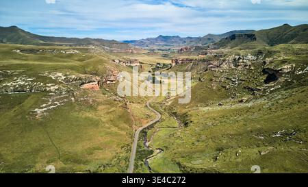 Wide Scenic Landscape. Peaceful Valley Stretching With Narrow Road Amidst Open Fields And Gentle Hills Stock Photo