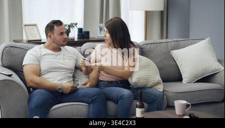 Argument, cellphone and couple on sofa in home with relationship problem, cheating or affair conflict. Fighting, phone and man with woman for marriage Stock Photo