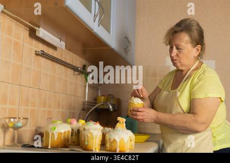 Female baker finishing Easter cakes, cozy home atmosphere Stock Photo