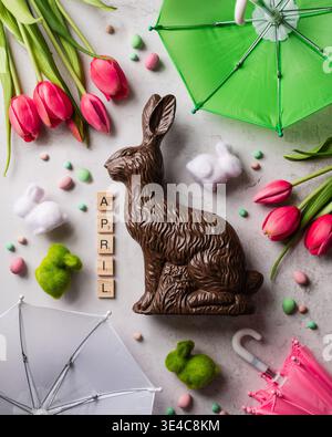 Top view of Easter bunnies, eggs, tulips and umbrellas for April. Stock Photo