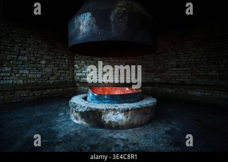 Large indoor fire pit inside stone shelter with glowing embers. Stock Photo