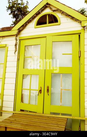 Wooden cottage exterior wall with a white window frame and green plants. Concept of rustic living, cozy home atmosphere, and traditional rural archite Stock Photo