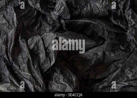 Texture of crumpled black paper with many folds and creases for background and overlay. The lighting show details in the material Stock Photo