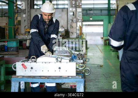 Industrial engineers and technicians discussing machine operation while inspecting equipment in a manufacturing factory || Model released Stock Photo