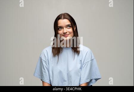 Young woman smiling while looking up and away, thinking about ideas, future, and aspirations Stock Photo