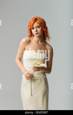 A young woman in a strapless dress and flowing red hair embodies spring charm. Stock Photo