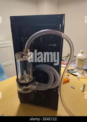 Detail of a custom water cooling system assembly with an external reservoir and D5 pump unit mounted on a black computer case using flexible transpare Stock Photo