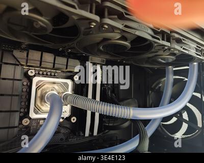 Close-up of a custom liquid cooling system installation on a gaming PC motherboard, showing the CPU water block, flexible tubing, and top-mounted 360m Stock Photo