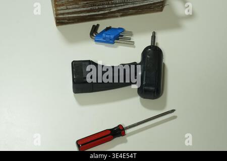 Black drill, screwdriver, and tool kit rest on white surface. No people appear in the photo, so no emotions to describe. This image suits DIY, repair, Stock Photo