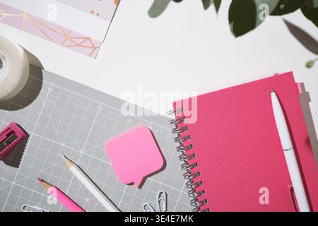 Pink workspace flat lay with notebook and clips for creative planning on white background. Copyspace. Stock Photo