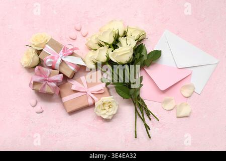 Composition with gift boxes, white rose flowers and envelopes on pink grunge background Stock Photo