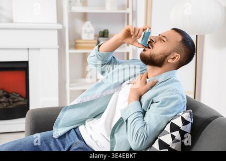 Young man with asthma attack using inhaler at home Stock Photo