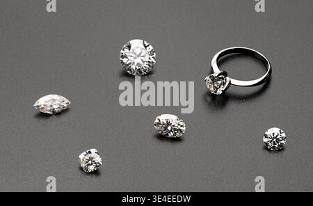 Diamonds and ring on dark surface. Loose stones and set ring show sparkle. Professional photography for jewelry ads or editorial use Stock Photo