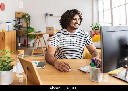 Young Indian man using computer in modern home office Stock Photo
