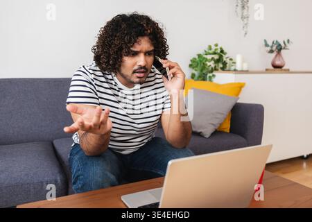 Young Indian man focused while working on laptop Stock Photo