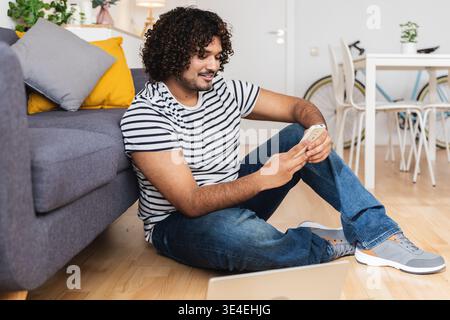 Young Indian man sitting on floor using phone Stock Photo
