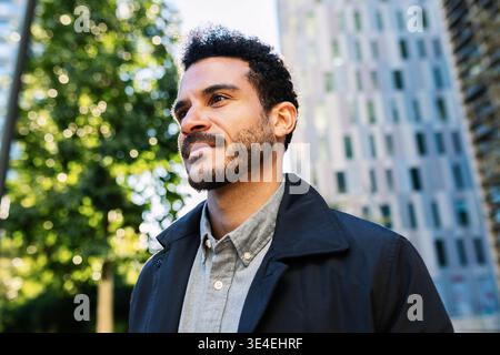 Portrait of happy adult man looking away at city street Stock Photo