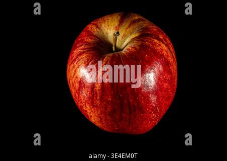 Single ripe apple on dark background with soft reflection, symbol of healthy diet and natural nutrition Stock Photo