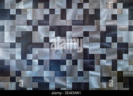 Brushed metal tiles forming an abstract checkered pattern on the wall Stock Photo