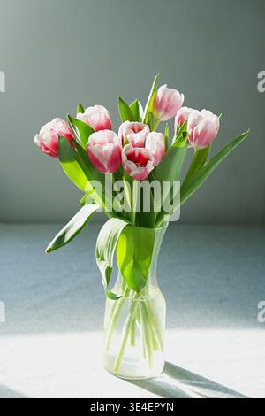 A bouquet of pink tulips in a glass vase on a tray background. High quality photo Stock Photo