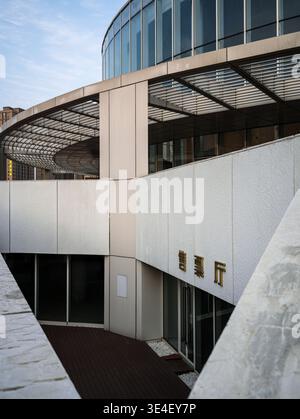 Wuhan, China - April 3, 2025: Modern curved building featuring a ticket office entrance at Dongxihu Cultural Center. The image shows white concrete fa Stock Photo