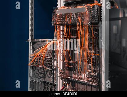 Two server racks with orange cables. Data center's core network switch with numerous computers and routers - data center'd high-speed architecture. Stock Photo