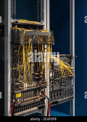 Two server racks with bright yellow cables. Data center's core network switch with numerous computers and routers - high-speed modular architecture. Stock Photo