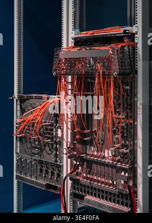 Two server racks with orange cables. Data center's core network switch with numerous computers and routers - high-speed modular architecture. Stock Photo