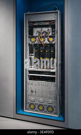 Industrial server rack and power distribution unit: cooling fans, power modules, complex wiring, housed in a modern recessed wall with blue accents. Stock Photo