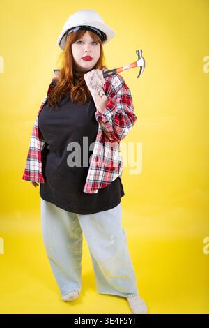 Woman wearing hard hat holding hammer ready for work Stock Photo