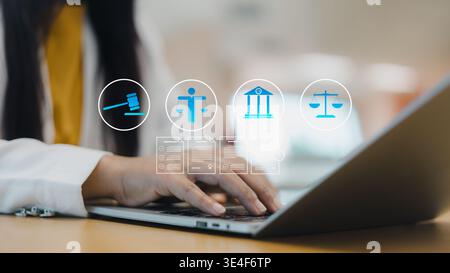 Asian female lawyer using a laptop with digital law icons, gavel, and scales of justice. Concept of online legal services, compliance, and cyber law t Stock Photo