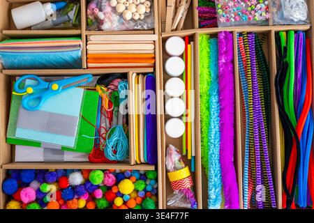 Organized craft kit with scissors paper glue beads and colorful materials in storage box. Kids education creativity and hands on learning concept. Stock Photo