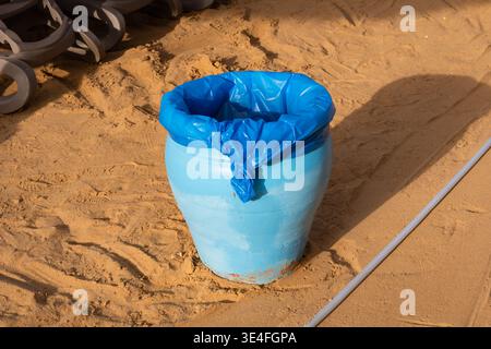 Blue plastic garbage bin with a liner on a sandy beach in Sharm El Sheikh Egypt to keep the resort clean. Stock Photo