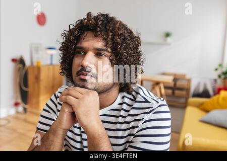 Young Indian man thinking at desk in home office Stock Photo