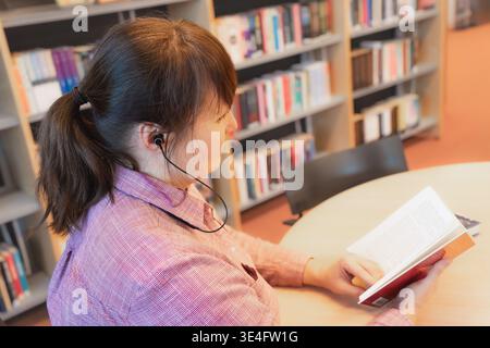 Cognitive focus midlife learner sitting at library table reading book with concentration and steady attention reflecting disciplined study routine for Stock Photo